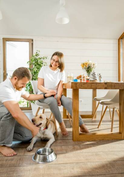 Husband and wife with their white labrador retriever enjoying their new durable pet-friendly laminate kitchen flooring